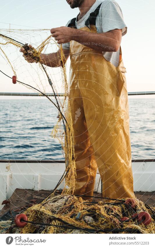 Anonymer Fischer, der vom Segelboot aus im offenen Meer fischt Boot MEER Fischen Netz Schoner Arbeit Uniform Fokus männlich Soller Balearen Mallorca Wadenfisch