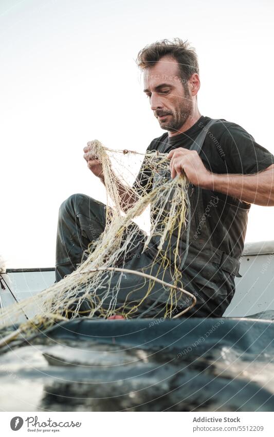 Mann entwirrt Fischernetzfäden, um bei Tageslicht Fische zu fangen Netz Fischen Boot Wasser Schiffsdeck Gerät Natur männlich Verkehr außerhalb nass aqua Sommer