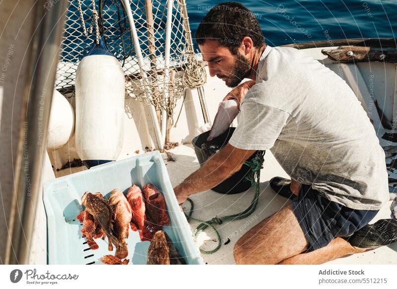 Konzentrierter Fischer in der Nähe eines Containers mit Fischen Mann Boot Sommer MEER ernst Konzentration Gefäße männlich Soller Mallorca Baleareninsel