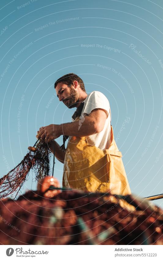 Mann, der ein Netz aus einem Segelboot im Meer zieht Fischer ziehen Fischen aufbinden Boot Trawler Schürze männlich Soller Balearen Mallorca Wadenfisch jagen