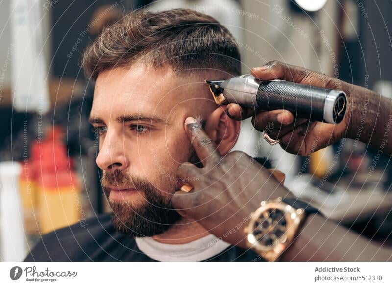 Schwarzer Barbier beim Trimmen der Haare eines jungen Mannes Männer Friseur Klient Haarschnitt entgittern Behaarung Trimmer Barbershop Genauigkeit Schönheit