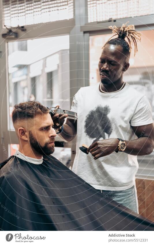 Mann bekommt professionellen Haarschnitt im Friseursalon Männer Klient entgittern Behaarung Trimmer Barbershop maskulin jung männlich rassenübergreifend