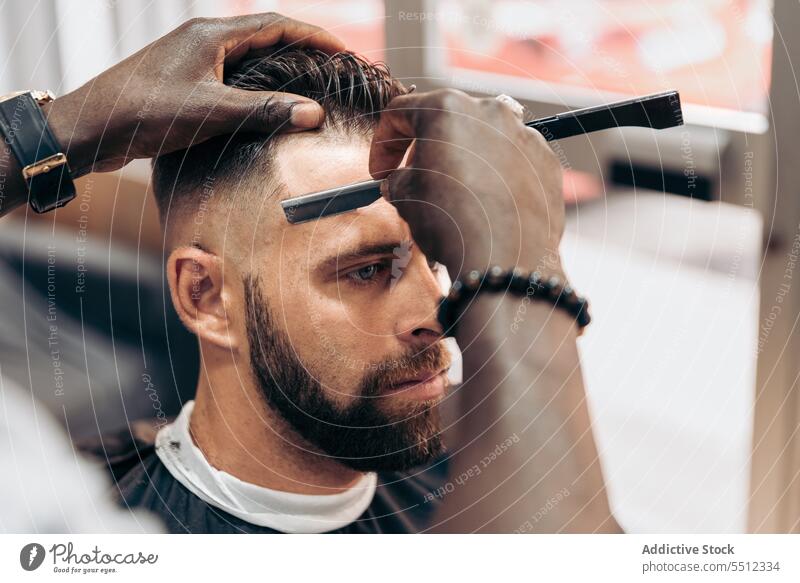 Barbier rasiert das Haar eines Kunden mit einem Rasiermesser Männer Friseur Klient Haarschnitt Rasierer Rasieren Barbershop Behaarung maskulin professionell