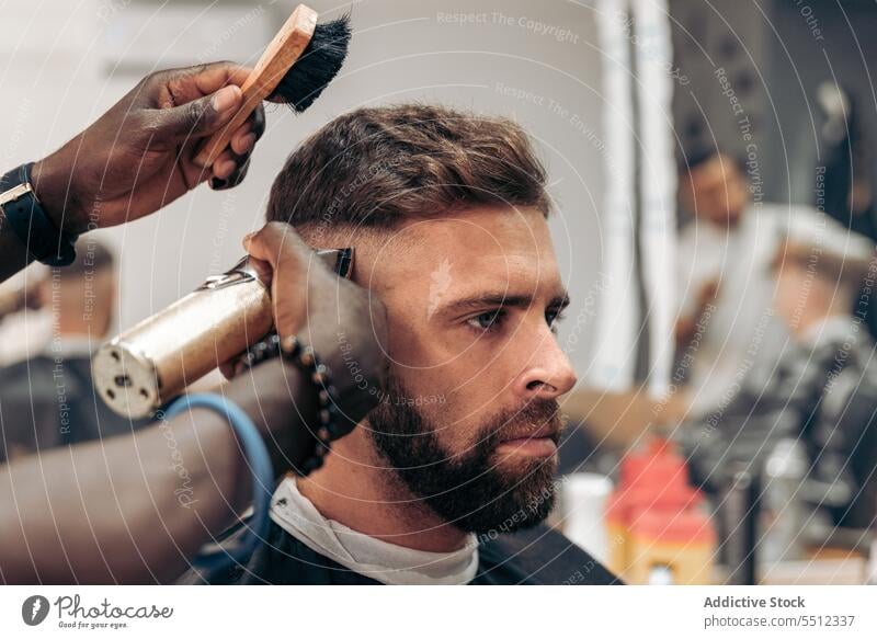 Mann bekommt professionellen Haarschnitt im Friseursalon Männer Klient Bürste entgittern Behaarung Trimmer Barbershop maskulin jung männlich rassenübergreifend