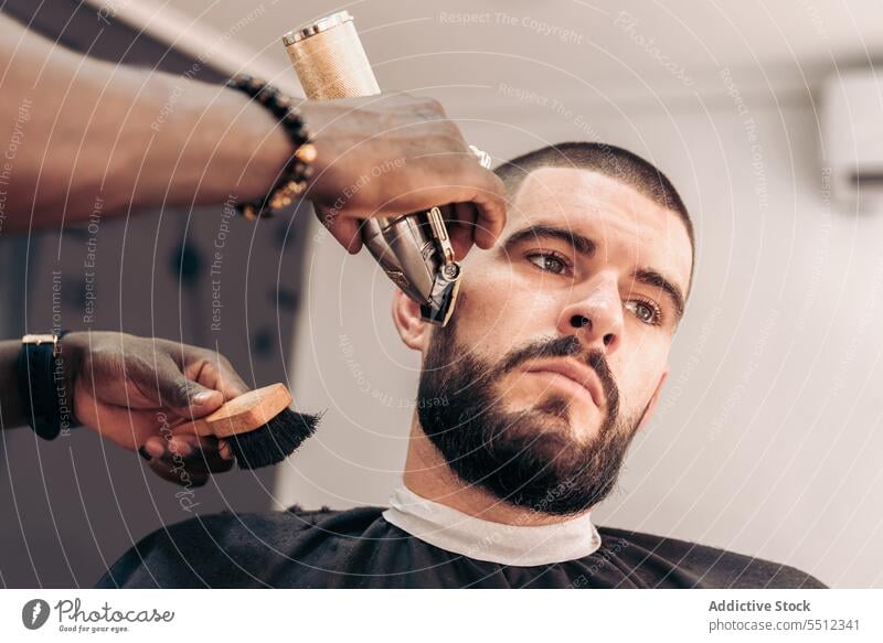 Professioneller Barbier rasiert den Bart eines Kunden in einem Barbershop Männer Friseur Klient Rasieren Vollbart Rasierer brutal Schönheit Pflege jung männlich