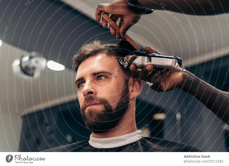 Schwarzer Barbier beim Trimmen der Haare eines jungen Mannes Männer Friseur Klient Haarschnitt entgittern Behaarung Trimmer Barbershop Genauigkeit Schönheit