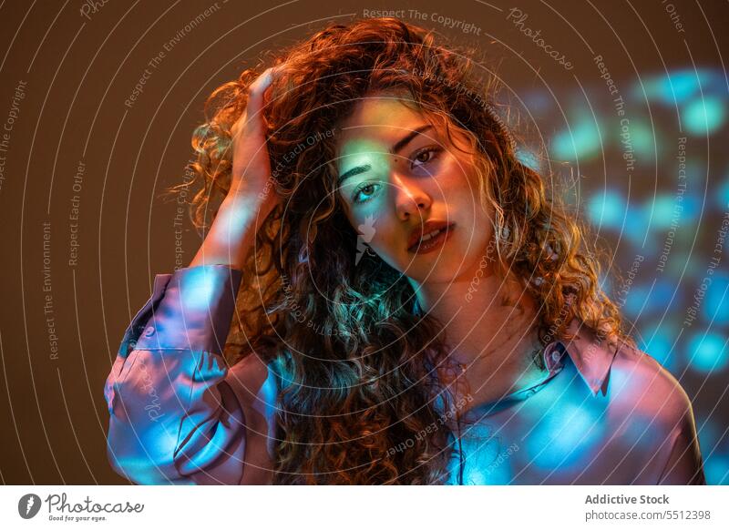 Attraktive Frau mit lockigem Haar in einem Raum mit Neonlicht Porträt Haare berühren ausrichten fixieren krause Haare Einfluss leuchten neonfarbig Punkt
