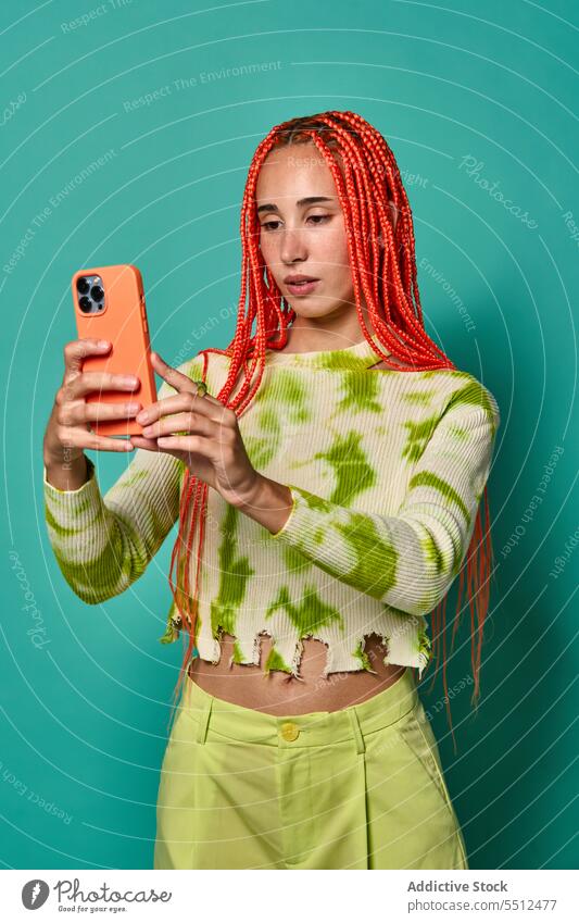 Stilvolle Frau mit Afrozöpfen, die ein Selfie mit ihrem Smartphone macht benutzend fotografieren stylisch Studioaufnahme Model soziale Netzwerke charismatisch