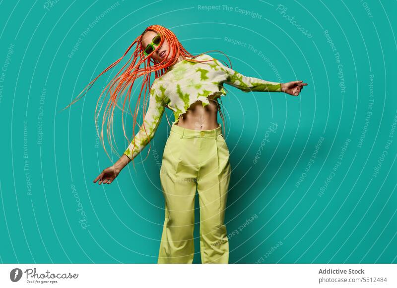 Stilvolle Frau in grünem Outfit und Sonnenbrille selbstbewusst stylisch Mode Model Studioaufnahme emotionslos cool lebhaft Vorschein jung springen Afro-Zöpfe