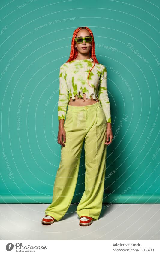 Stilvolle Frau in grünem Outfit und Sonnenbrille selbstbewusst stylisch Mode Model Studioaufnahme emotionslos cool lebhaft Vorschein jung Afro-Zöpfe Langarm Top