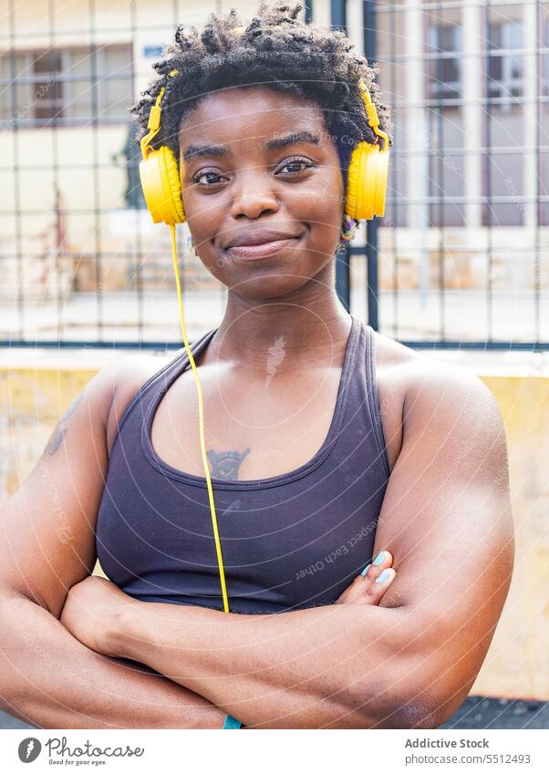 Zufriedene afroamerikanische Frau, die auf der Straße Musik hört meloman Kopfhörer zuhören benutzend Melodie Audio verträumt genießen sportlich Stil ethnisch
