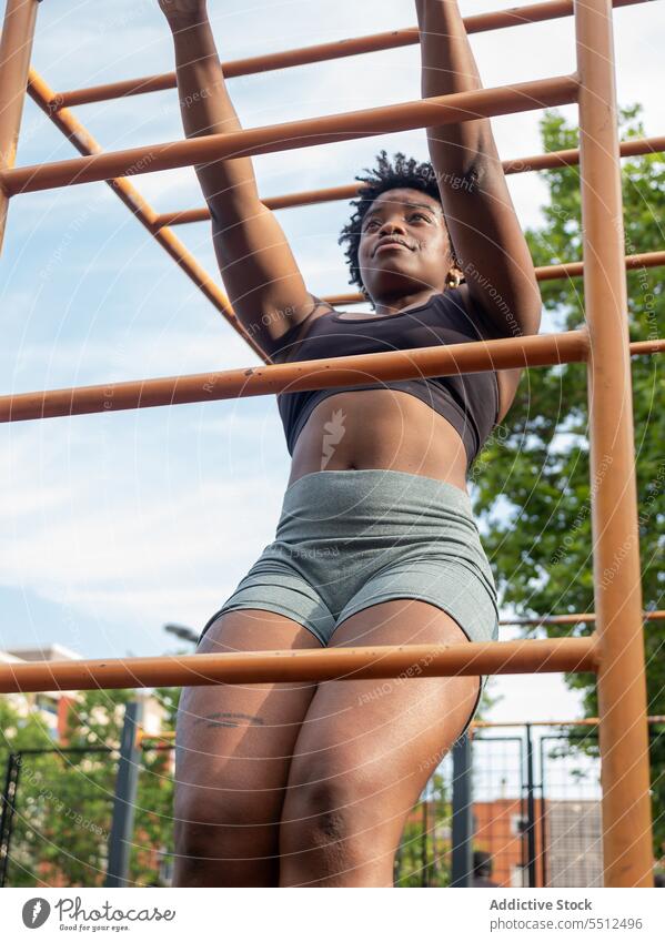 Fokussierte starke junge schwarze Frau bei Übungen an einer Metallstange in einer offenen Turnhalle Sportlerin ziehen Training Bar Fitnessstudio muskulös Athlet