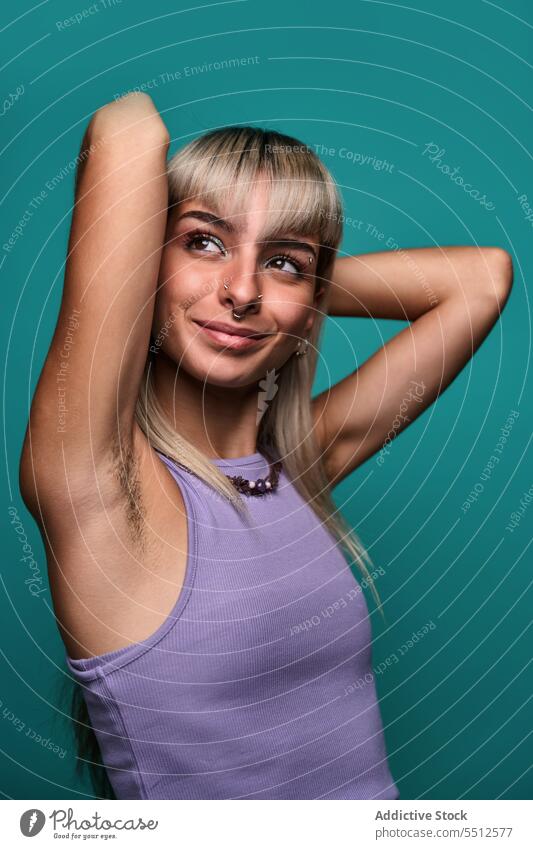 Selbstbewusst lächelnde Frau mit haariger Achselhöhle Hipster körperpositiv Hand hinter dem Kopf Arme hochgezogen Porträt natürlich Körper akzeptieren