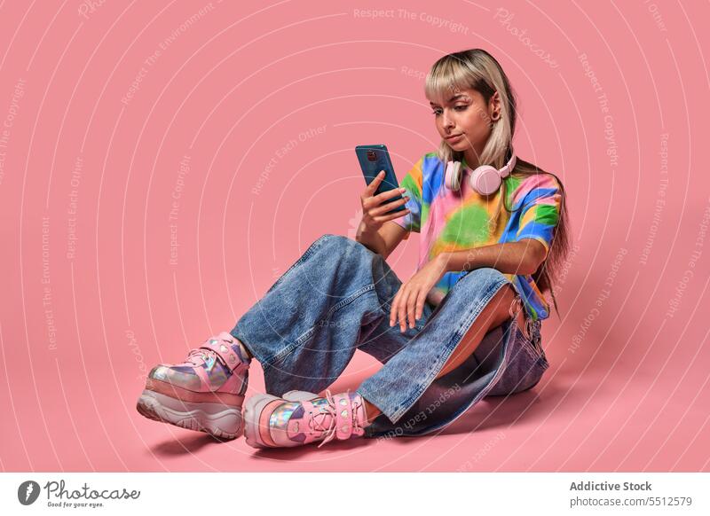 Junge Hipsterin benutzt Smartphone im Studio Frau benutzend Surfen Internet Kopfhörer Studioaufnahme Piercing Nachricht jung blond trendy Streetstyle urban Stil