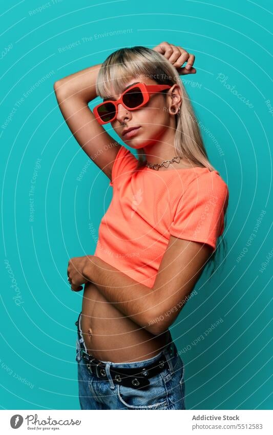 Selbstbewusste trendige Hipster-Frau mit Sonnenbrille Hand auf Kopf trendy Streetstyle Körperhaltung Studioaufnahme informell Subkultur selbstbewusst