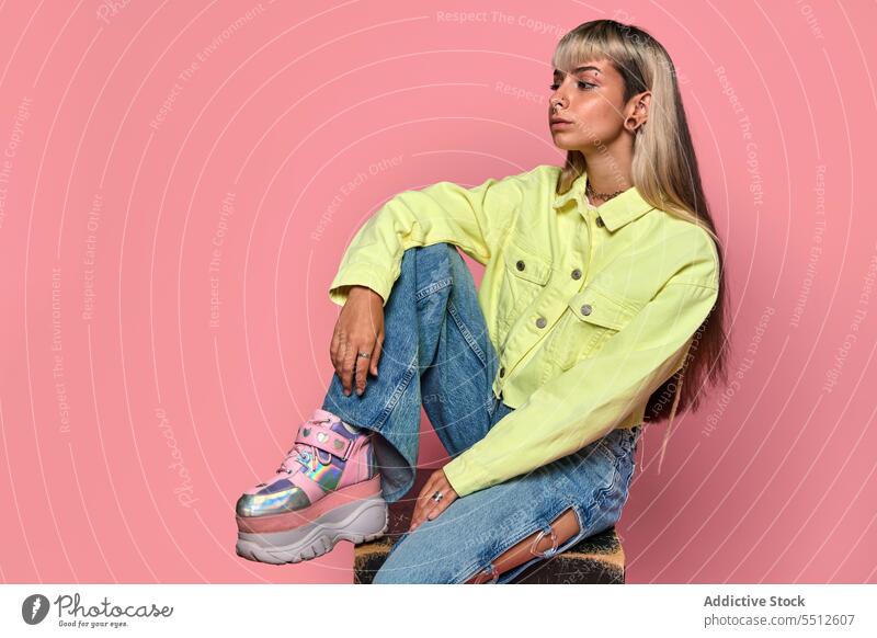 Selbstbewusster junger weiblicher Hipster sitzt auf einem Würfel Frau trendy Körperhaltung Studioaufnahme Model informell Subkultur Piercing selbstbewusst