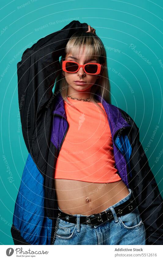 Selbstbewusste trendige Hipster-Frau mit Sonnenbrille Hand auf Kopf trendy Streetstyle Körperhaltung Studioaufnahme informell Subkultur selbstbewusst