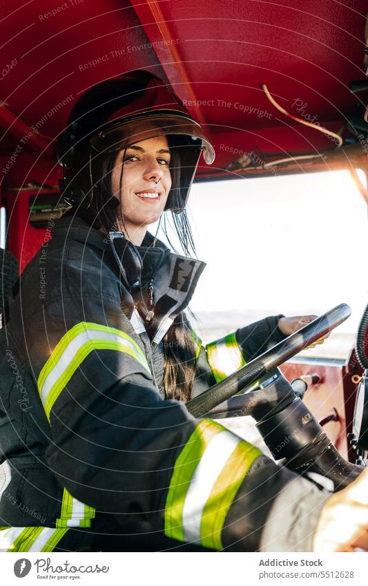 Lächelnde Feuerwehrfrau fährt Feuerwehrauto Frau Feuerwehrmann Fahrer Laufwerk Lastwagen Fahrzeug Dienst Mut Glück jung Schwarzes Haar behüten furchtlos Verkehr