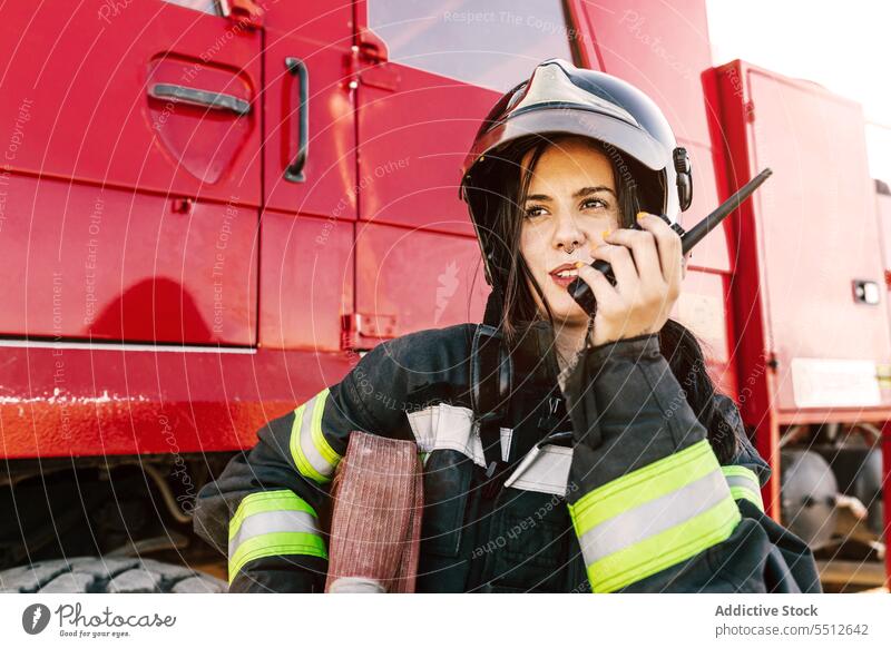 Weiblicher Feuerwehrmann spricht in der Nähe des Löschfahrzeugs über Funk Frau Walkie-Talkie Radio Kommunizieren Schlauch Lastwagen Notdienst Job jung
