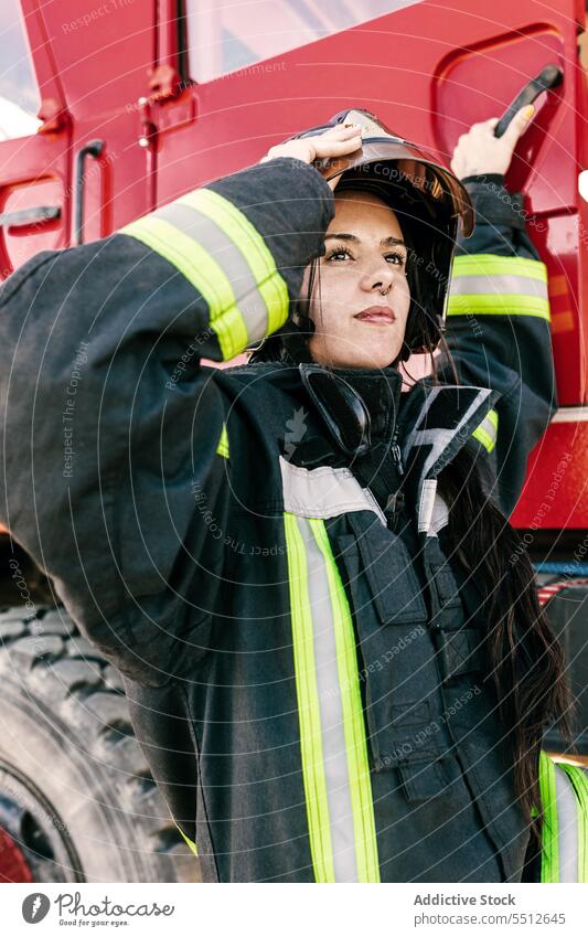 Mutige Feuerwehrfrau steigt ins Feuerwehrauto ein Frau Feuerwehrmann Lastwagen vorbereiten ausrichten Schutzhelm Beruf behüten jung Schwarzes Haar Sicherheit