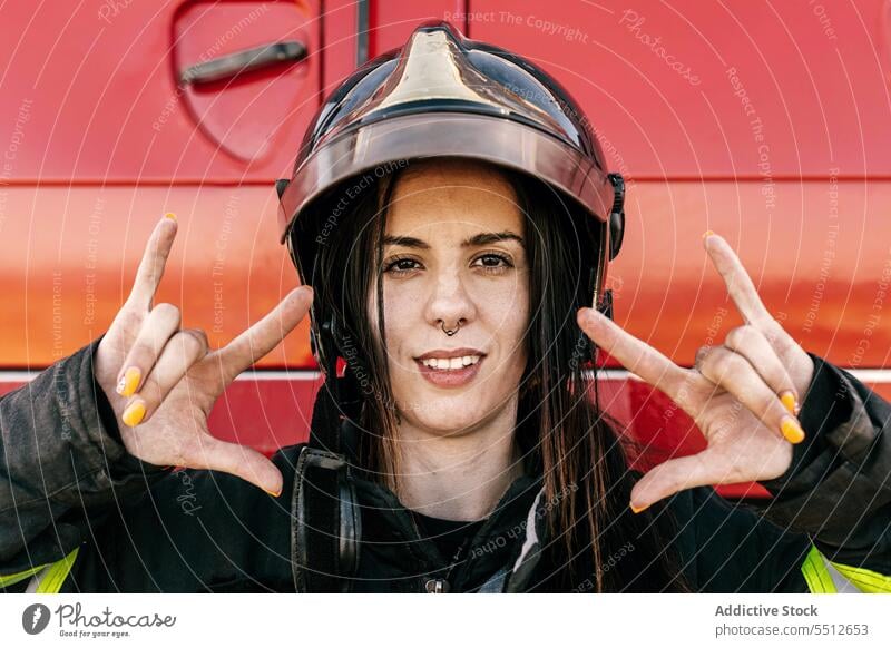 Frau mit Helm und Hupenzeichen Schutzhelm gestikulieren Porträt Rock and Roll Zeichen Sicherheit behüten Feuerwehrmann PKW Fahrzeug Uniform zeigen Verkehr Beruf