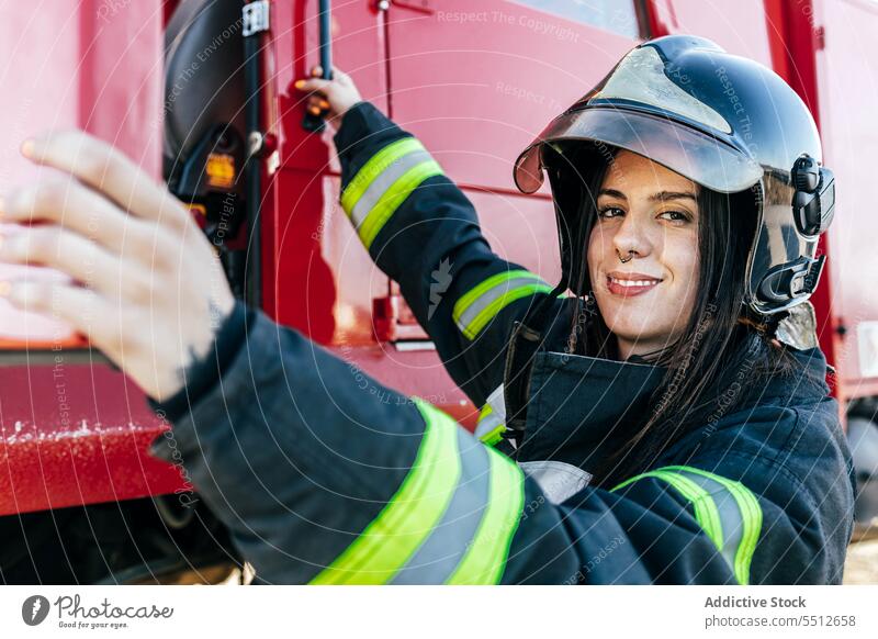 Lächelnde Feuerwehrfrau beim Einsteigen in ein Feuerwehrauto Frau Feuerwehrmann bei der Arbeit Fahrer Lastwagen Personal Rettungsdienst Beruf Glück jung