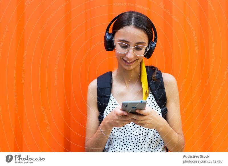 Fröhliche Frau, die ein Smartphone benutzt und Musik hört Kopfhörer zuhören benutzend Apparatur Glück heiter Browsen Mobile Gerät jung Lächeln Surfen