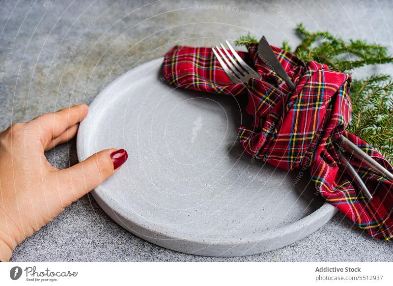 Crop-Frau stellt Teller auf den Tisch Gabel umhüllen Messer Weihnachten Tanne dienen Besteck Keramik kariert Zweig nadelhaltig Utensil grün Speise Fichte