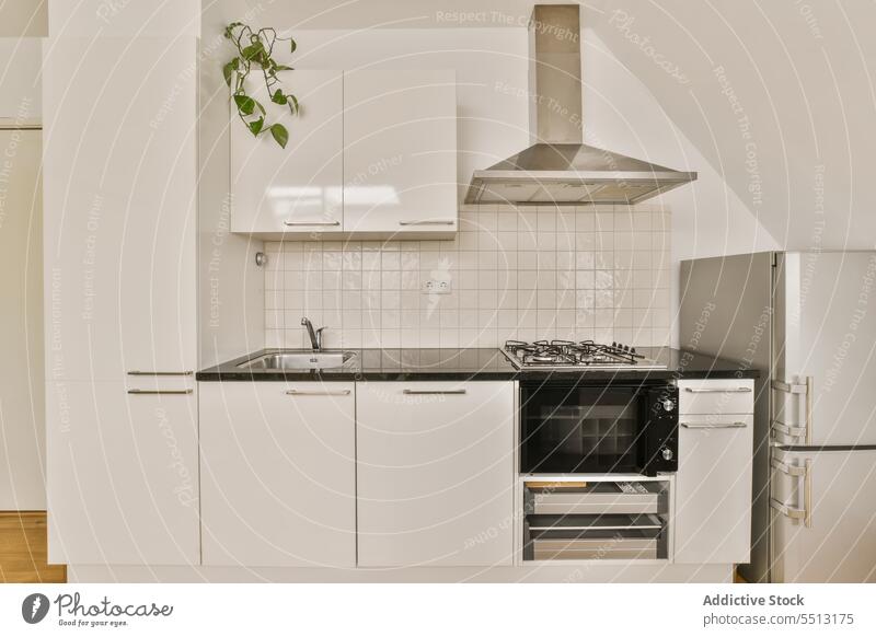 Küche mit schwarzer Arbeitsplatte und weißen Schränken zu Hause Herd Kabinett Kühlschrank Ofen Kapuze modern Innenbereich heimwärts Fliesen u. Kacheln Wand