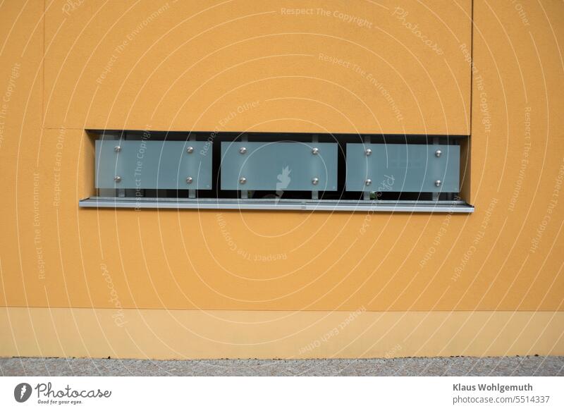 Geschmackvoll verkleidete Maueröffnung an einem modernen Gebäude. Mattglas und Edelstahl bilden einen schönen Kontrast zum orangenen Mauerwerk Architektur
