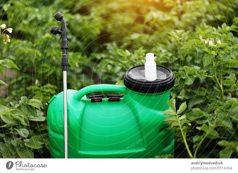 Weiße kleine Flasche von Pestizid, Herbizid für den Schutz von Pflanzen vor Krankheiten und Schädlingen mit Mock up steht auf Container Sprayer auf natürliche grüne Garten Hintergrund. Landwirtschaftliche saisonale Arbeit