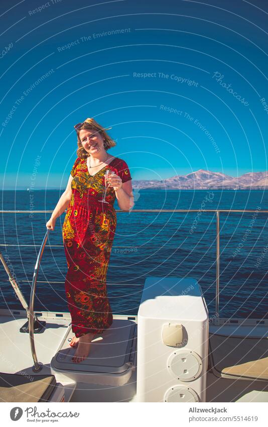 Portrait einer Frau mittleren Alters in einem roten Kleid mit einem Sektglas auf einem Boot Sommer Sommerurlaub Sommerzeit sommerlich Urlaub Urlaubsstimmung