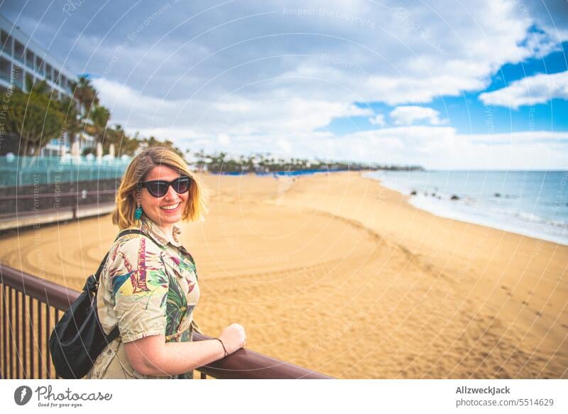 Portrait einer Frau mittleren Alters mit Sonnenbrille und Kleid an einem breiten Strand von Lanzarote Porträt kurzärmelig Urlaub Urlaubsstimmung Urlaubsfoto