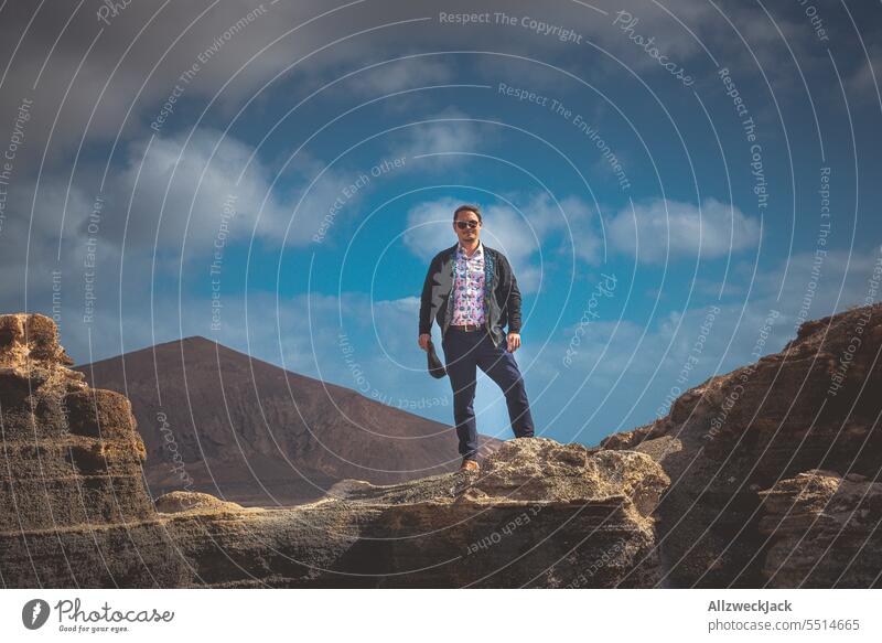 Mann mittleren Alters steht auf einem Felsen vor blauem Himmel mit Wolken Lanzarote posierend Natur Outdoor Aufstieg städter stadtmenschen Schönes Wetter Sommer