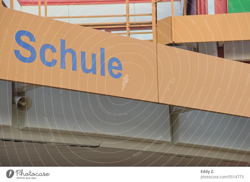 Schrift mit dem Wort Schule auf einer metallisch wirkenden, leicht verblassten orangefarbenen gitterartigen Struktur, der diagonal verläuft. schule Schulgebäude