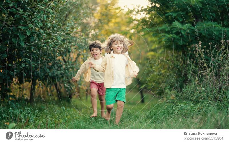 Spielende Kinder, die auf einem Grundstück im Landhaus rennen. Ökologisches Leben außerhalb der Stadt bezaubernd Hinterhof schön Junge heiter Kindheit Europa