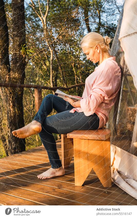 Frau liest ein Buch auf der Glamping-Terrasse glamourös Urlaub lesen Freizeit ruhen Wochenende Ausflug räkeln Sonnenlicht Herbst Leseratte Etage Bank Windstille