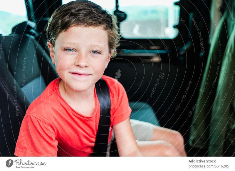 Glückliches, süßes Kind im Auto sitzend mit angelegtem Sicherheitsgurt im Tageslicht Junge PKW Lächeln Sitz Gurt Fahrzeug heiter Verkehr Straße lässig positiv