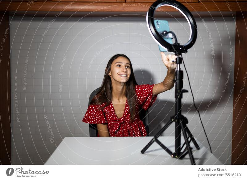 Frau nimmt Video mit Smartphone in dunklem Raum auf Blogger Influencer live Aufzeichnen benutzend Ringlampe vlog dunkel Apparatur soziale Netzwerke Lächeln