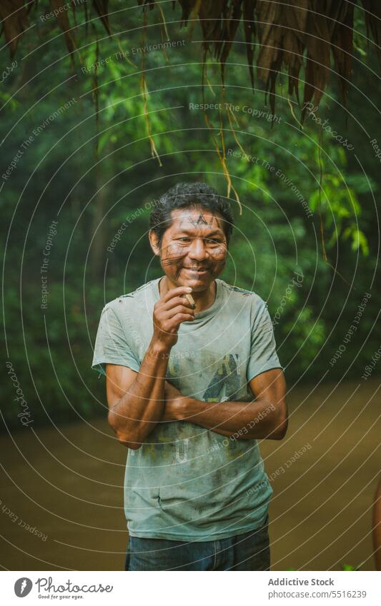 Lächelnder ethnischer Mann auf dem Lande, der raucht Rauch lokal Landschaft tropisch Fluss sich[Akk] entspannen Porträt exotisch Regenwald Fischer freundlich