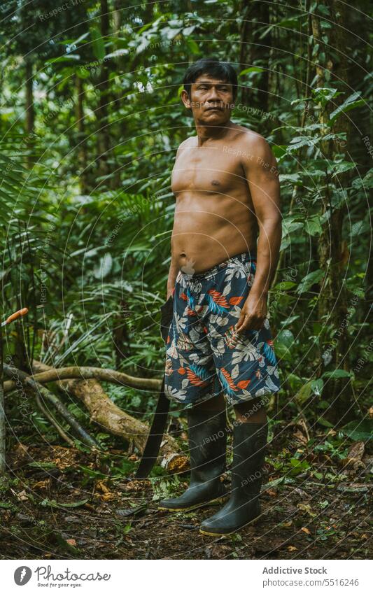 Hemdloser Stammesangehöriger im Regenwald stehend Mann Tribal Dschungel tropisch Natur Buchse Wald ohne Hemd Grün lokal Holz exotisch Boden Job Machete Klima