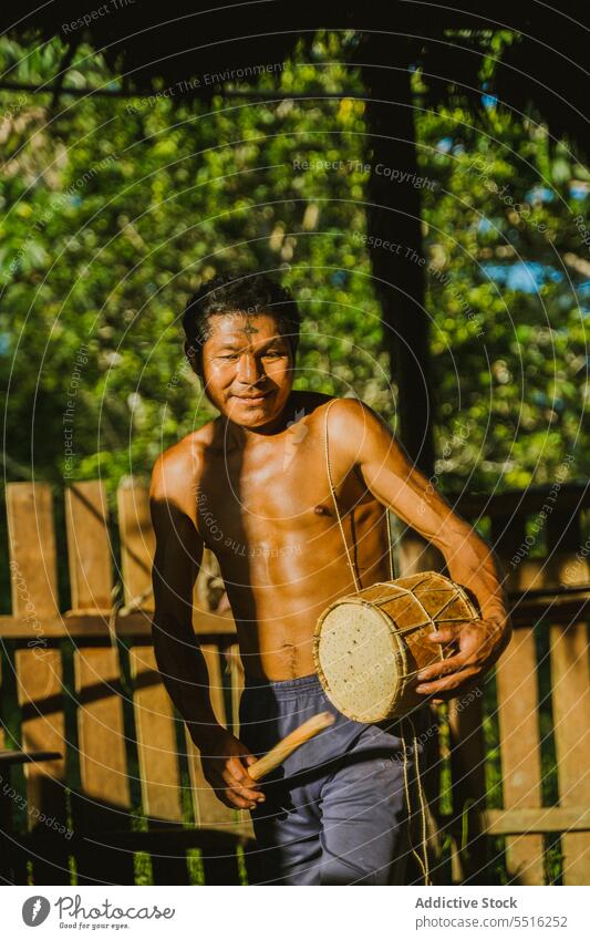 Einheimischer Mann spielt Trommel im Sonnenlicht Stamm Dorf spielen lokal einheimisch ländlich Spaziergang heimatlich authentisch Natur tropisch Tradition