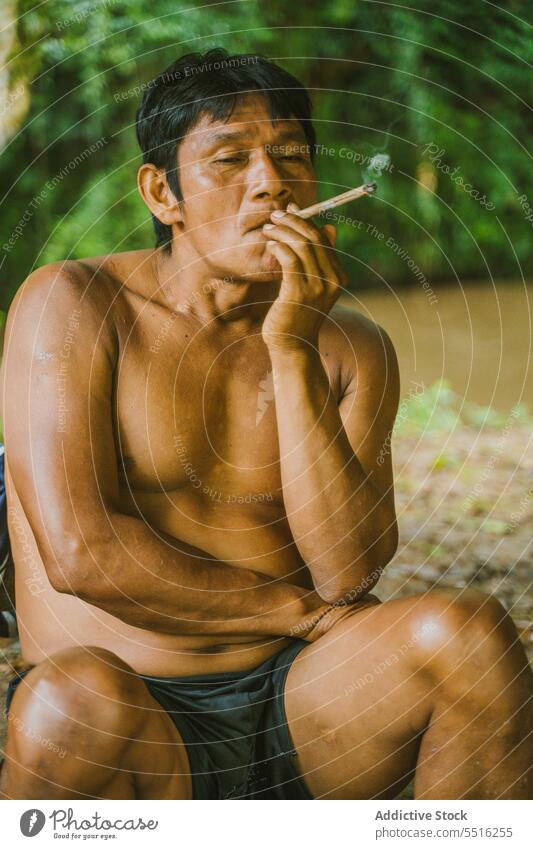 Ethnischer Ureinwohner raucht in Ruhe Mann ruhen lokal Natur Rauch Fluss Zigarette Landschaft sich[Akk] entspannen Ufer Regenwald Flussufer Fischer ländlich