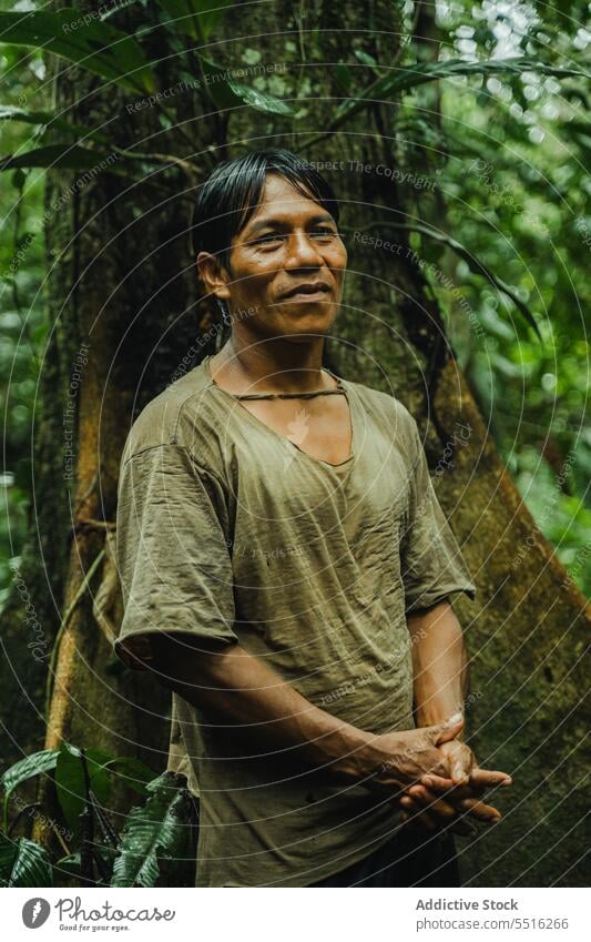 Ethnischer Mann im Wald stehend tropisch Stamm Farbe exotisch Natur Dschungel grün männlich ethnisch Lächeln froh Tradition Pflanze Sommer Baum Umwelt Flora
