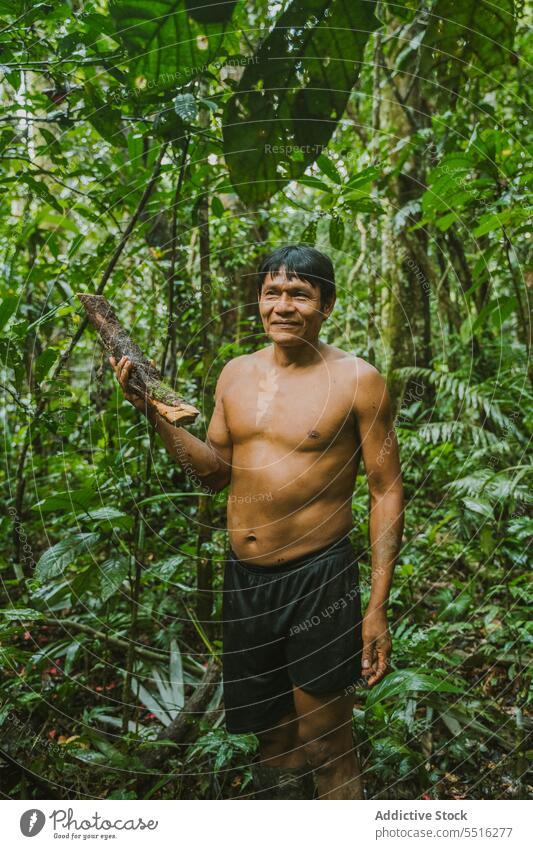 Lächelnder Stammesangehöriger mit Brennholz in der Natur Mann Dschungel Totholz abholen exotisch Umwelt Holz lokal Wohnsiedlung pflücken Dorf national Tradition