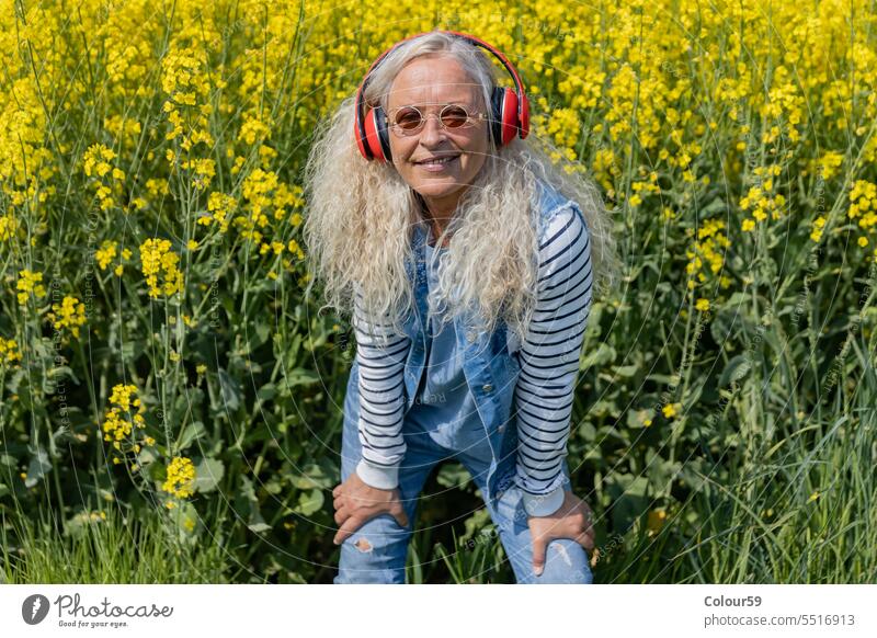 Fröhliche Seniorin mit roten Kopfhörern Frau reif Kaukasier Lächeln schön Musik lässig Natur alt gealtert heiter Porträt Lifestyle Blick Erwachsener Glück