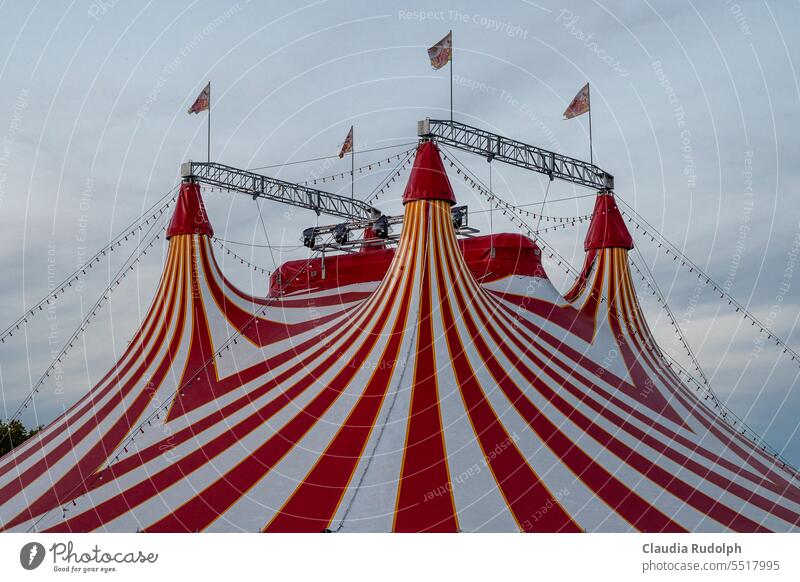 Dach eines  rot-weiß gestreiften Zirkuszelts mit wehenden Fahnen Zikuszelte Zelt Himmel Show Veranstaltung Kultur Jahrmarkt Spitze Freizeit & Hobby Wolken