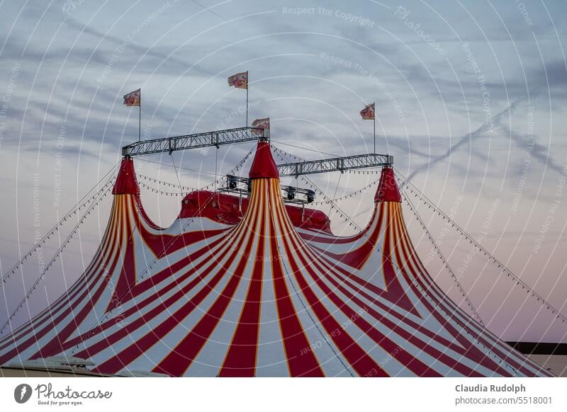 Dach eines rot weiß gestreiften Zirkuszeltes vor abendlichem Himmel Zelt Veranstaltung Show Entertainment Kultur Jahrmarkt Wolken Spitze Feste & Feiern