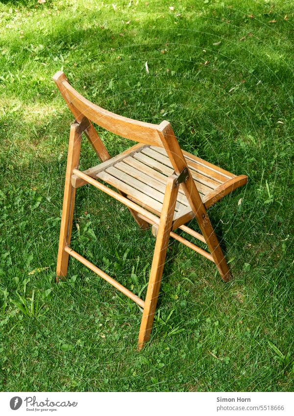 Klappstuhl aus Holz steht auf einer Wiese Rasenfläche Sitzplatz Gras Farbkontrast menschenleer Garten Stuhl Sitzgelegenheit Pause draußen abseits abseits stehen