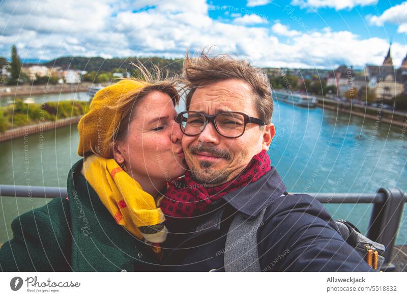 Pärchen macht bei herbstlichem Wetter und starkem Wind ein Selfi, während sie ihn küsst Deutschland Koblenz selfie Paar Paare Paare mittleren Alters pärchen